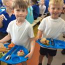 Two boys carrying lunch to their table